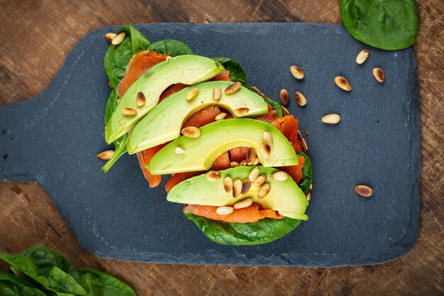 Panino al pane integrale di salmone e avocado con vista dall'alto di spinaci