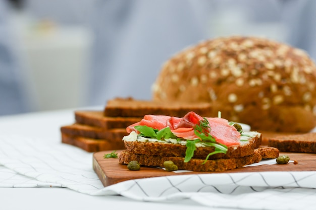 Panino al salmone affumicato con formaggio, pistacchi e foglie di insalata, pane nero