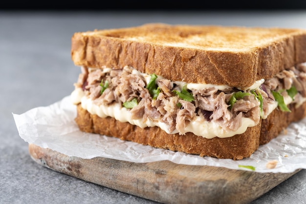 Panino al tonno con maionese e verdure su sfondo grigio pietra