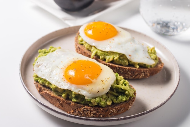 Panino all'uovo di avocado con un bicchiere d'acqua. Concetto di sana colazione leggera. Toast integrali