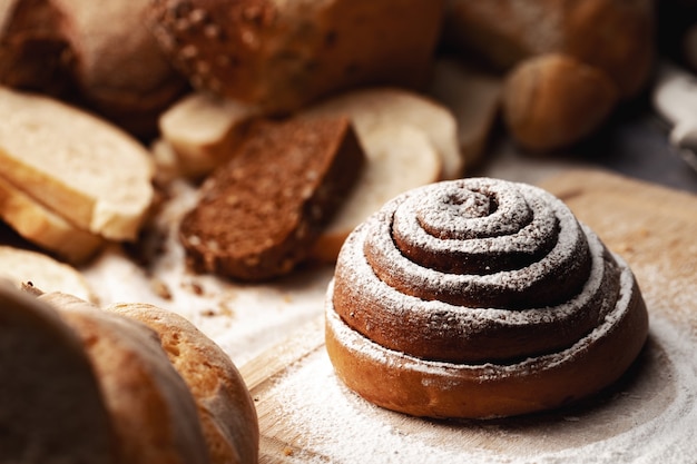 Panino alla cannella fresco con zucchero in polvere su tavola di legno