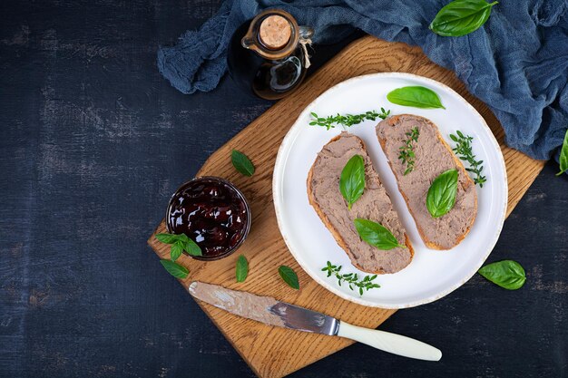 Panino alla griglia con pate con fegato di pollo e olive su sfondo scuro