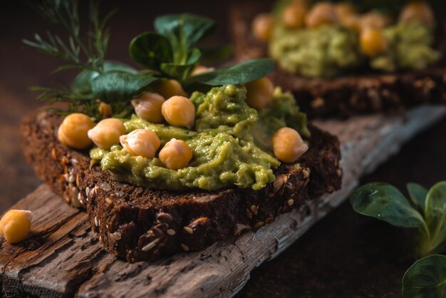 Panino aperto con crema di avocado e verdure sulla tavola di legno