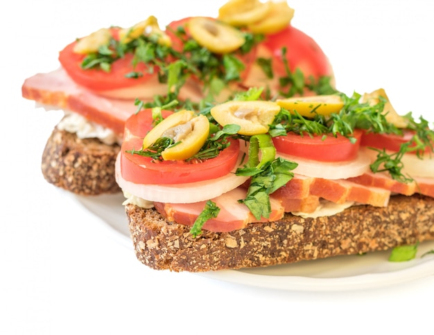 Panino appena preparato con il prosciutto su un piatto isolato su fondo bianco