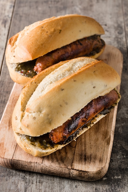 Panino argentino tradizionale di Choripan con la salsa di chimichurri e del chorizo sulla tavola di legno