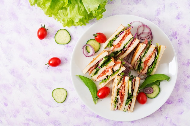 Panino club con petto di pollo, pancetta, pomodoro, cetrioli e erbe