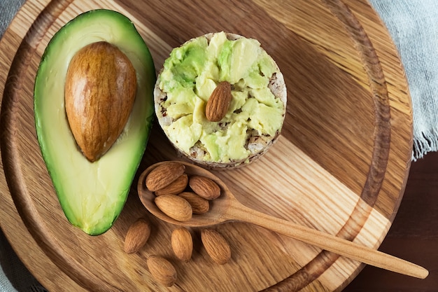 Panino con avocado e mandorle su un fondo di legno marrone