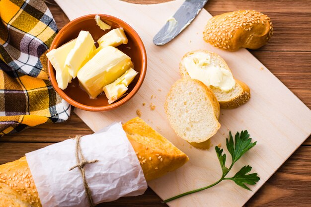 Panino con burro e baguette affettate su un tagliere. Vista dall'alto