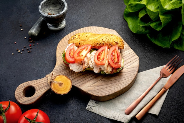 Panino con carne macinata alle erbe e pomodori su fondo scuro