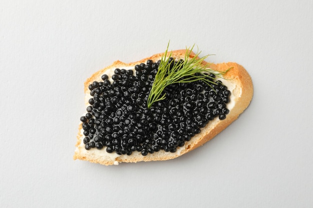 Panino con caviale nero e aneto su sfondo bianco, vista dall'alto