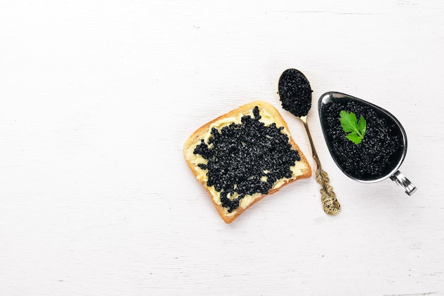 Panino con caviale nero e burro su fondo di legno Vista dall'alto Spazio libero per il testo