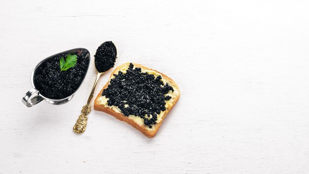 Panino con caviale nero e burro su fondo di legno Vista dall'alto Spazio libero per il testo