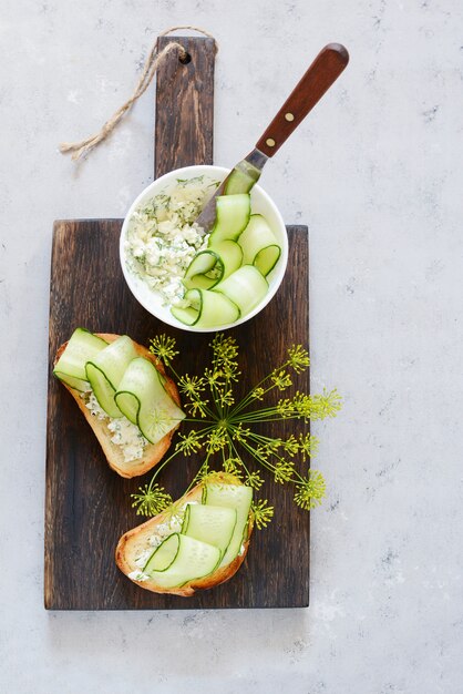 Panino con crema di formaggio e cetriolo fresco. Avvicinamento. Panino vegetariano fitness con ricotta, cetriolo e aneto, colazione. Sandwich inglese