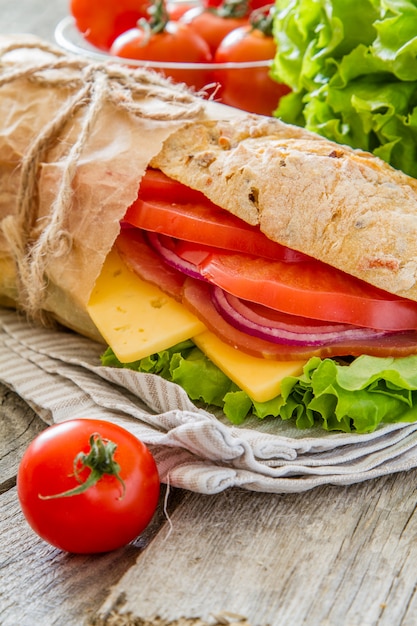 Panino con formaggio e prosciutto, insalata e pomodori