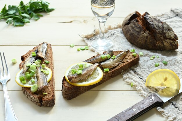 Panino con gli spratti. Spratto sott'olio. Su uno sfondo di legno.