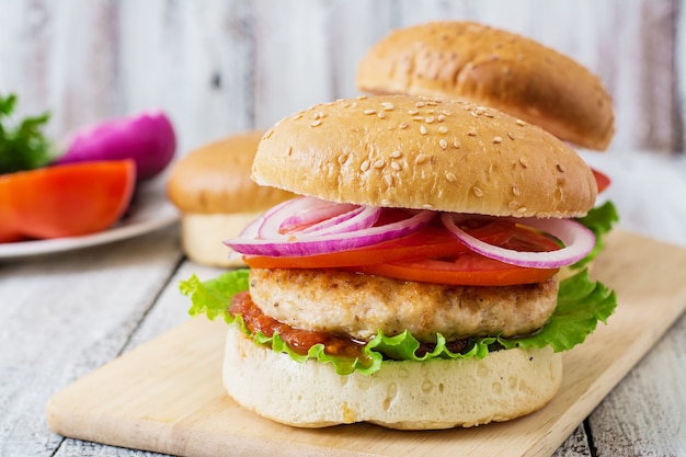 Panino con hamburger di pollo, pomodori, cipolla rossa e lattuga