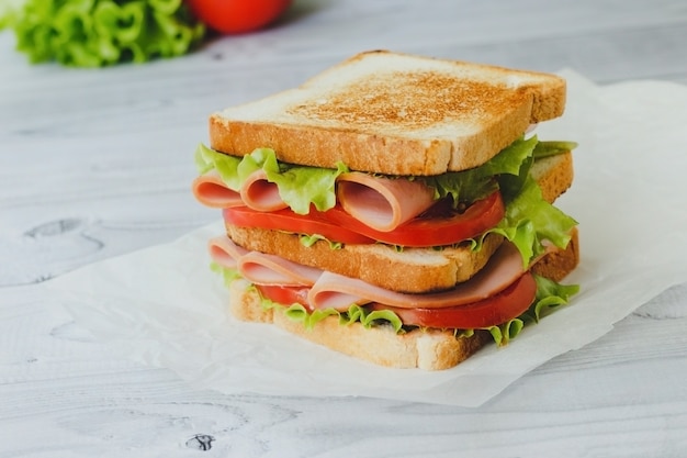 Panino con insalata di carne pomodoro verdure su pane di segale su fondo di legno