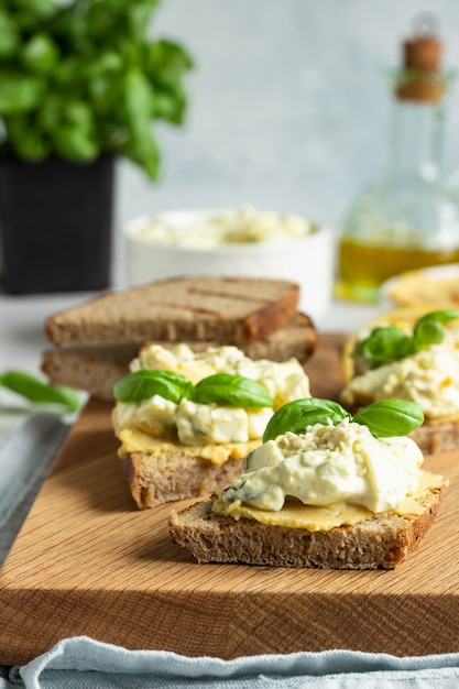 Panino con insalata di uova, avocado e hummus con basilico e ingredienti freschi per preparare panini.