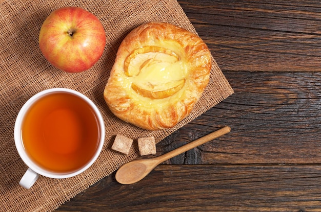 Panino con mela e tazza di tè sul tavolo in legno scuro vista dall'alto