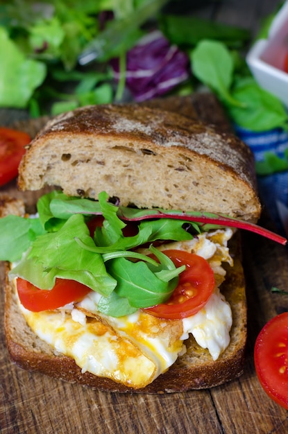 Panino con pane nero, uova e pomodori.