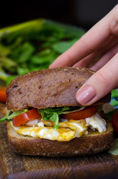 Panino con pane nero, uova e pomodori.