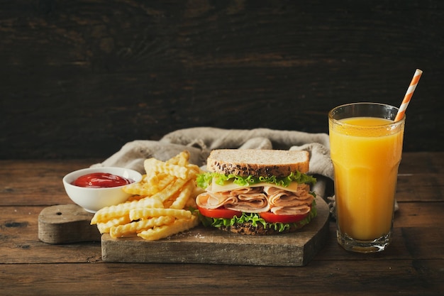 Panino con patate fritte al prosciutto e bicchiere di succo d'arancia