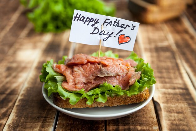 Panino con pesce rosso su pane di segale con foglia di lattuga Congratulazioni per la festa del papà