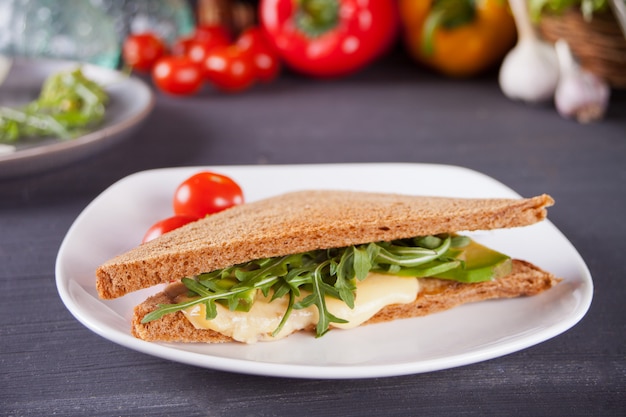 Panino con petto di tacchino, formaggio, lattuga, rucola, pomodori e cipolla su un piatto nero