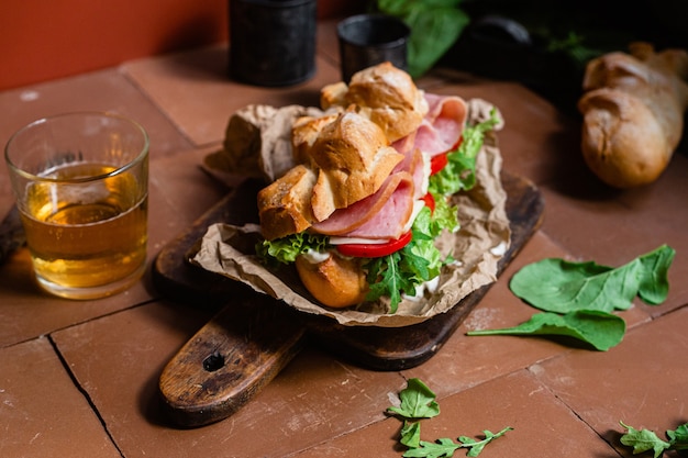 Panino con prosciutto formaggio pomodoro e lattuga su fondo scuro