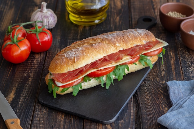 Panino con prosciutto, pomodori, rucola e formaggio. Mangiare sano. Dieta.