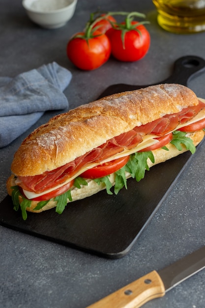 Panino con prosciutto, pomodori, rucola e formaggio. Mangiare sano. Dieta.