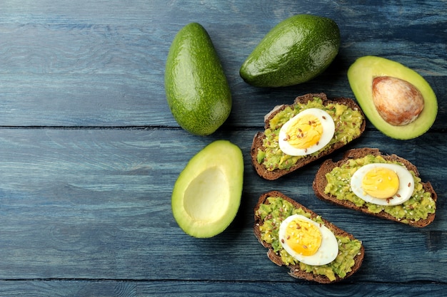 Panino con purea di avocado e uova su un tavolo di legno blu con spazio per il testo. vista dall'alto