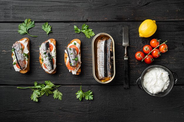 Panino con set di pesce affumicato, su sfondo di tavolo in legno nero, vista dall'alto piatta