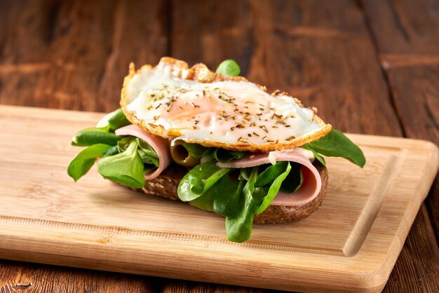 Panino con uova fritte e salsiccia su un tavolo di legno