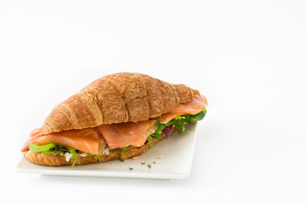 Panino del croissant con i salmoni e le verdure isolati sullo spazio bianco della copia