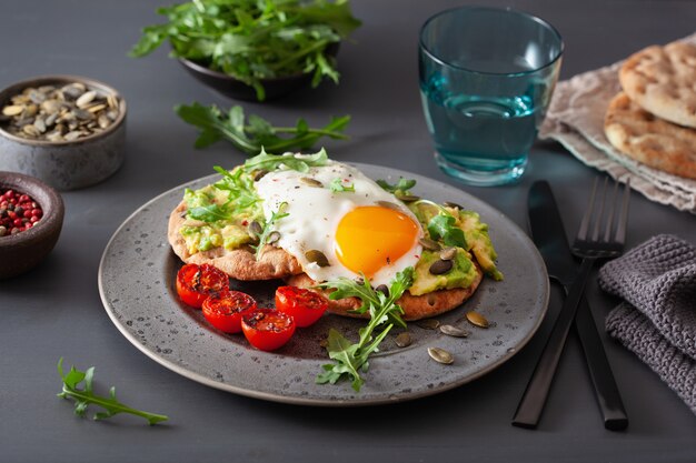 Panino dell'avocado della prima colazione con l'uovo fritto e il pomodoro