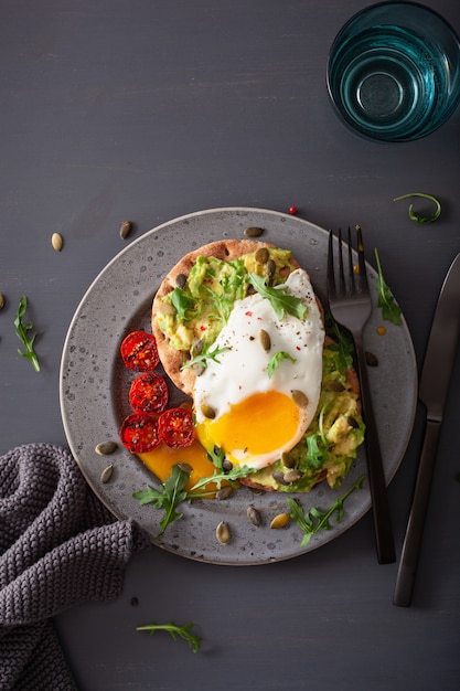 Panino dell'avocado della prima colazione con l'uovo fritto e il pomodoro