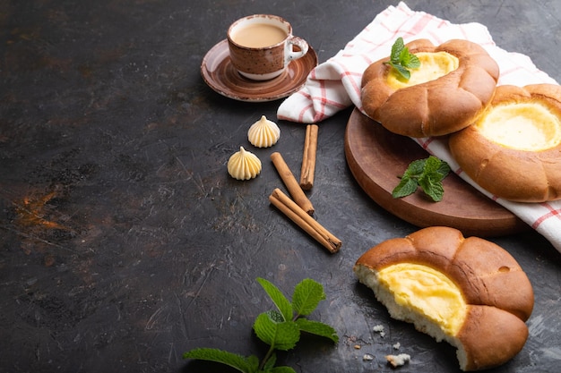 Panino di panna acida con una tazza di caffè su uno sfondo di cemento nero Spazio per la copia con vista laterale