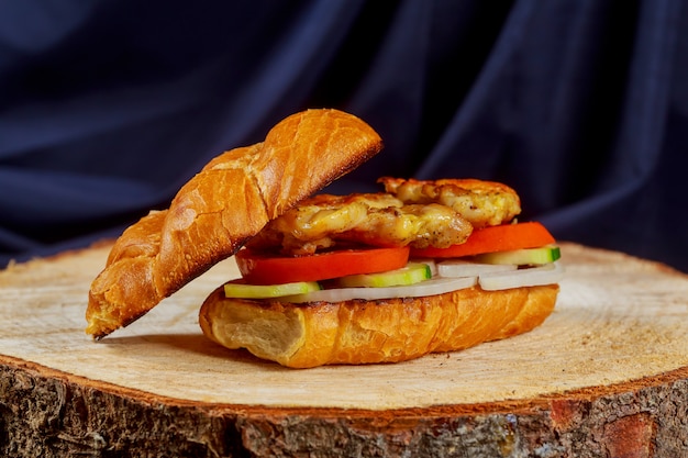 Panino di pollo con cetriolo di pomodoro cipolla su un supporto in legno