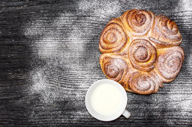 Panino dolce con zucchero a velo e tazza di latte sul tavolo