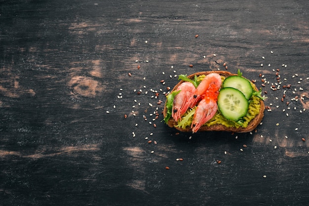 Panino hamburger con caviale di avocado di gamberi e cetriolo su sfondo di legno Vista dall'alto Spazio di copia