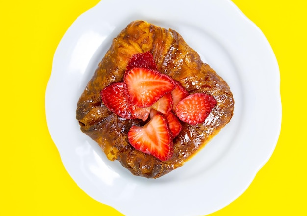 Panino o rotolo di pasta sfoglia Torta con fragole fresche Tentazione di dolci deliziosi e dessert su sfondo giallo Minimalismo Immagine originale e creativa Bella carta da parati alimentare