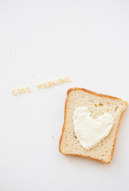 Panino per colazione a forma di cuore con iscrizione di buongiorno al formaggio