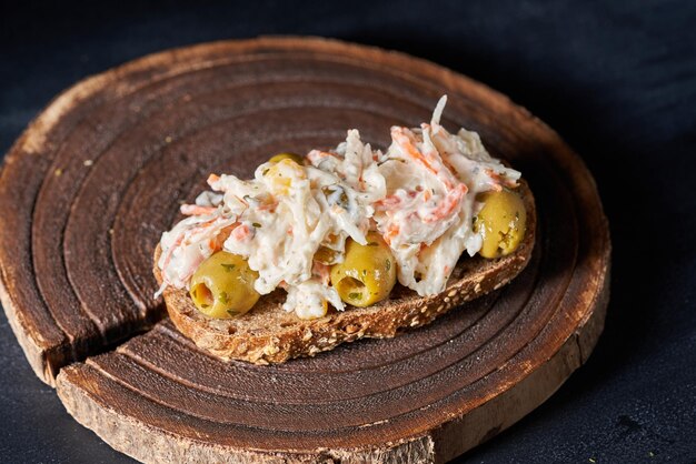 Panino pieno di insalata e olive su uno sfondo scuro