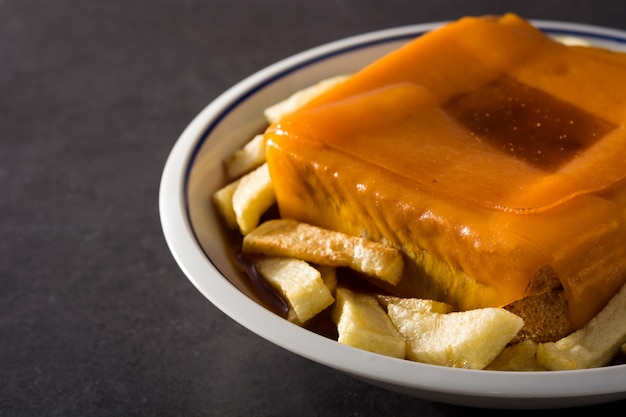 Panino portoghese tipico di francesinha con le patate fritte sul nero