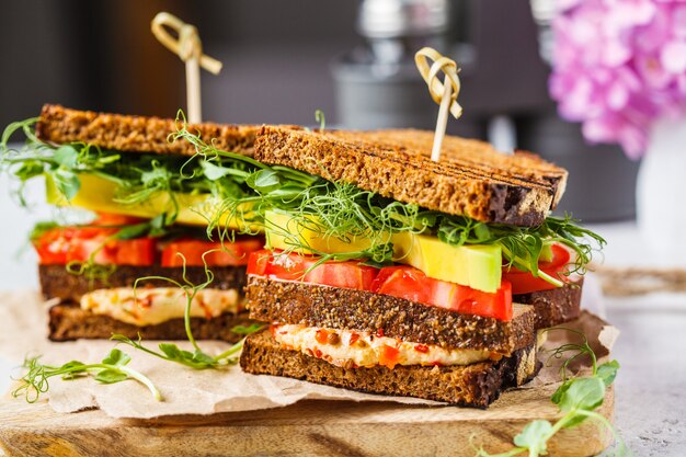 Panino vegano con tofu, hummus, avocado, pomodoro e germogli.