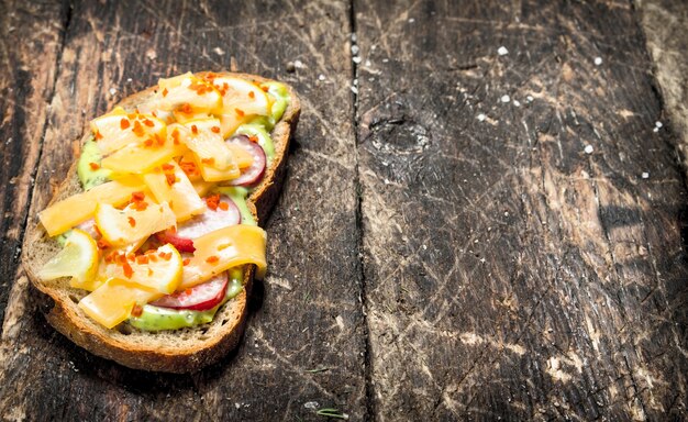 Panino vegetariano con formaggio, ravanello e salsa di erbe fresche sulla tavola di legno.