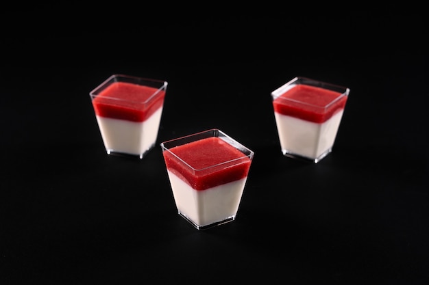 Panna cotta con marmellata rossa isolata sul nero.