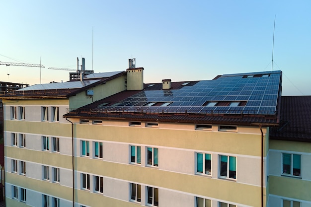 Pannelli solari fotovoltaici blu montati sul tetto di un edificio industriale per la produzione di energia elettrica pulita ed ecologica. Concetto di produzione di energia rinnovabile.