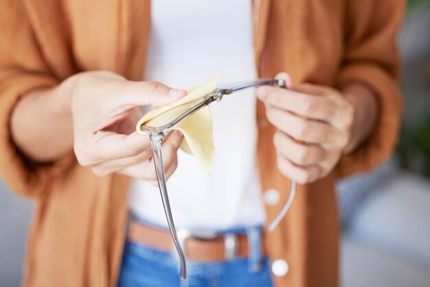 Panno per la pulizia degli occhiali e mani della donna che fanno la cura degli occhi con il tessuto per pulire la lente e il telaio Sporco di polvere e cura di una persona presso un optometrista o uno studio medico che si prepara per il test della vista per la salute